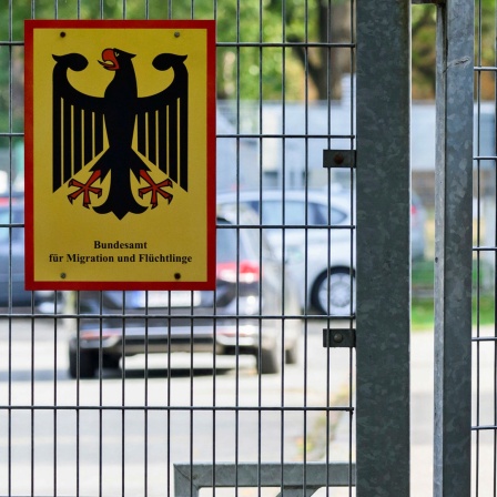 Ein Mann betritt neben einem Schild vom Bundesamt für Migration und Flüchtlinge die Landesaufnahmebehörde Niedersachsen am Standort Braunschweig.