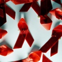 Viele rote Aids-Schleifen liegen auf einem Tisch. 