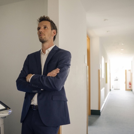 Bored businessman leaning against wall next to copying machine model released Symbolfoto property released