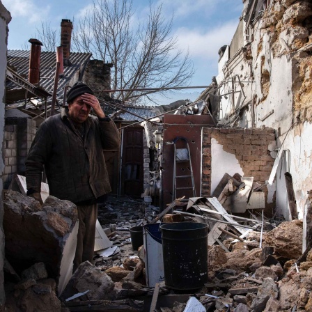Der 62-jährige Aleksei hält sich das Gesicht vor seinem zerbombten Haus in der Stadt Cherson.