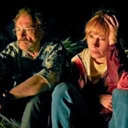 Eine Frau und ein Mann mit Brille im Dunkeln sitzen und schauen ernst - Josef Hader und birgit Minichmayr in "Andrea lässt sich scheiden" von Josef Hader