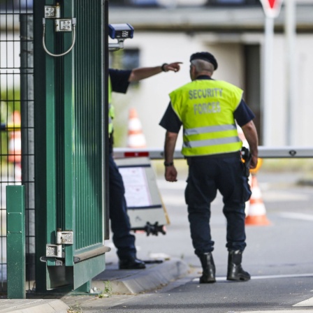 Sicherheitspersonal steht im Bereich der Einfahrt zur Nato Air Base, links der Hinweis auf den Security Alert State C.