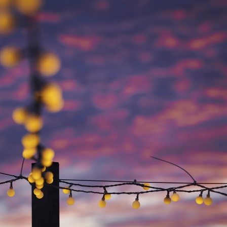 Das Beitragsbild des WDR3 Kulturfeature "Ziemlich nice - Die Gegenwart von Leif Randt ist pastellfarben" zeigt eine Lichterkette, die auf der Terrasse einer Bar hängt, vor farbigem Abendhimmel.