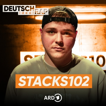 Stacks102 blickt direkt in die Kamera. Er trägt eine dunkle Baseballkappe rückwärts, einen olivgrünen Pullover mit einem hellen Aufdruck auf der Brust sowie eine schlichte goldene Halskette. Der Hintergrund ist dunkel und leicht verschwommen, mit einer intensiven Lichtquelle hinter ihm, die ein beleuchtetes Schild mit der Aufschrift „STACKS102“ zeigt. Darunter sieht man das Logo der ARD. 