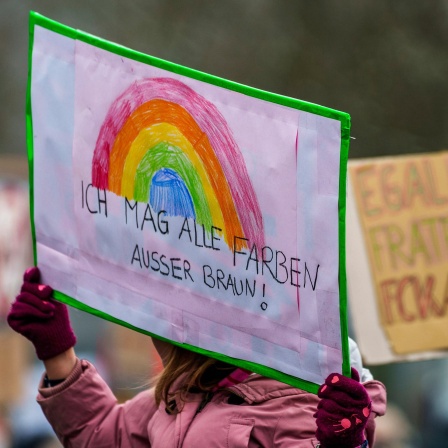 Ein Plakat "Ich mag alle Farben außer Braun!" wird auf einer Kundgebung gegen Rechtsextremismus  hochgehalten