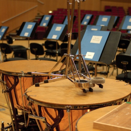 Pauken und Notenständer auf der Bühne eines Konzerthauses.