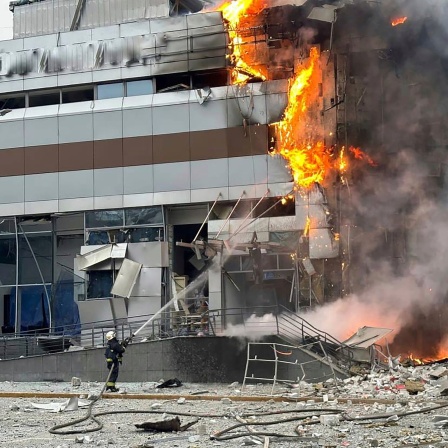 Feuerwehrleute arbeiten an einem Gebäude, das nach einem russischen Angriff in Kiew beschädigt wurde.