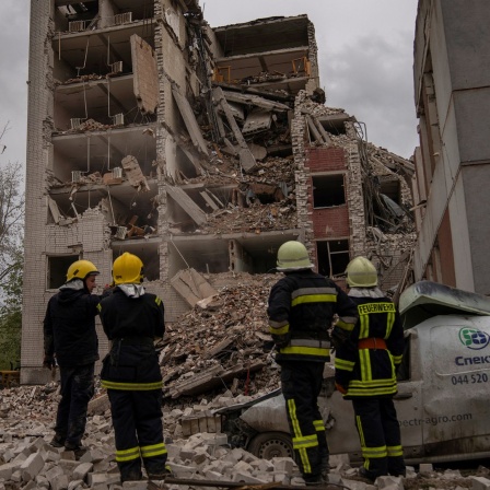 Tschernihiw: Feuerwehrleute stehen vor einem Gebäude, das durch russische Angriffe teilweise zerstört wurde.