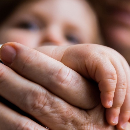 Die Hände von Enkelkind und Oma liegen ineinander