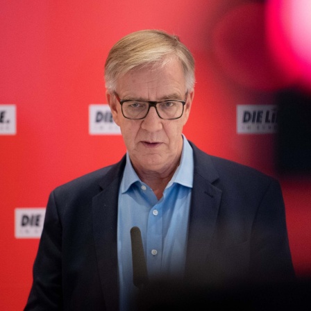 Dietmar Bartsch auf einem Podium mit dem Schriftzug "Die Linke" (2021).