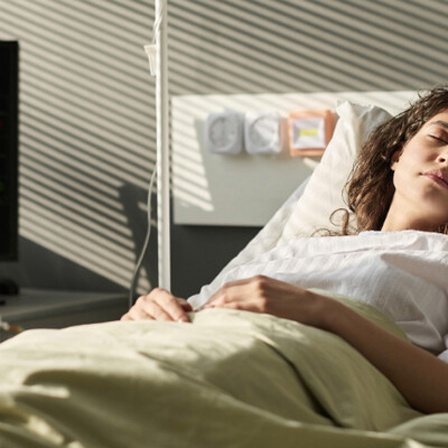 Frau schläft im Krankenhausbett