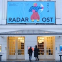 Über dem Eingang des deutsches Theaters hängt das Festivalplakat von "Radar Ost" mit einer Figur auf blauem Grund, die einen Faustschlag in Richtung Osten vollführt.