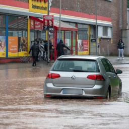 Passanten stapfen und fahren durch das Hochwasser in der Fischbachstraße in Saarbrücken. Nach starken Regenfällen steht diese teilweise unter Wasser.