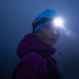 Eine Wanderin mit Stirnlampe auf einer nächtlichen Bergwanderung.