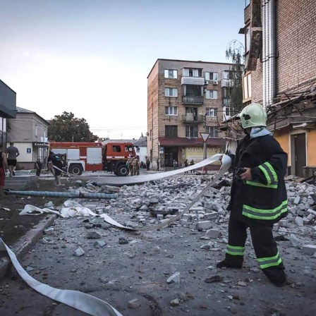 Rettungskräfte an einem Gebäude, das nach Raketenangriffen beschädigt wurde. 