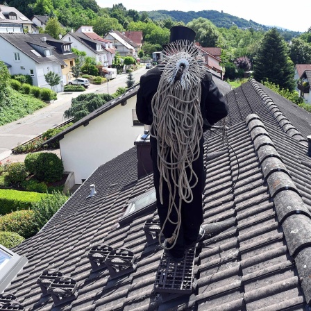 Schornsteinfeger auf dem Dach eines Hauses