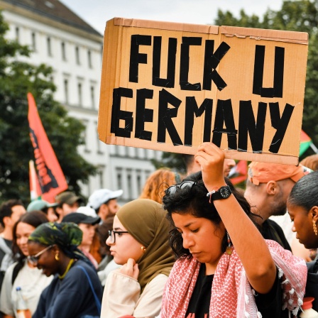 &#034;Fuck U (you) Germany&#034; steht auf einem Schild einer Teilnehmerin bei einer pro-palästinensische Demonstration in Kreuzberg