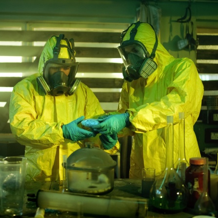 In einem Crystal-Meth-Labor. Zwei Menschen in Ganzkörperschutzkleidung packen die Droge in Tüten.