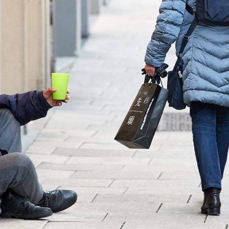 Ein Mann sitzt bettelnd in der Fußgängerzone 