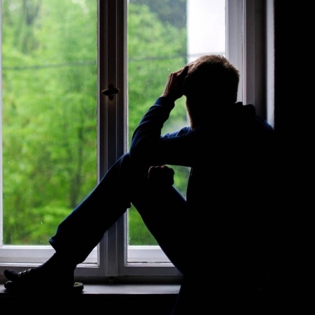 Ein Mann sitzt an einem Fenster und schaut raus