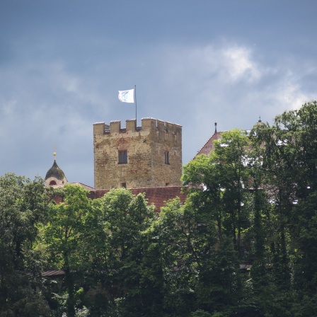 Turm des Schlosses Neubeuern hinter grünem Laub. | Bild: Colourbox