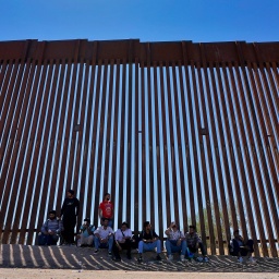 Das Beitragsbild des Dok5 "Auf Turnschuhen durch die Wüste" zeigt eine Gruppe Flüchtlinge im Schatten der amerikanischen Grenzmauer in der Region Tucson in 2023.