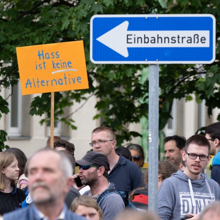 Teilnehmer einer Kundgebung stehen auf dem Pohlandplatz und halten ein Schild mit der Aufschrift "Hass ist keine Alternativ