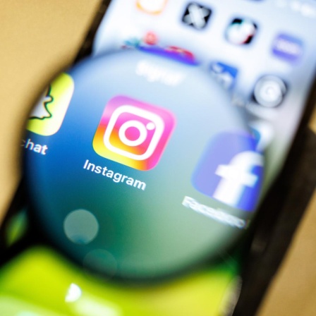 Das Logo der App Instagram ist am 29.12.2024 durch eine Lupe auf dem Display von einem Smartphone zu sehen. Instagram ist ein soziales Netzwerk mit Fokus auf Video- und Foto-Sharing, das vom Unternehmen Meta Platforms betrieben wird.