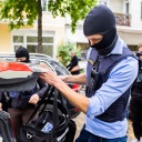 Ein Polizist stellt bei einer Hausdurchsuchung in Berlin-Kreuzberg eine Tasche in ein Fahrzeug. 