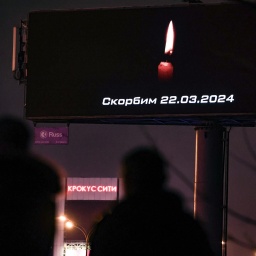 In Moskau laufen Menschen an einer Anzeigetafel vorbei, auf der eine Kerze für die Opfer des 22.03.2024 leuchtet. 