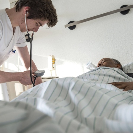 Ein Krankenpflegeschüler misst den Blutdruck eines Patienten.