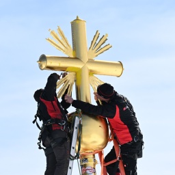 Die im Tal restaurierten Strahlen des Gipfelkreuzes der Zugspitze werden von Mitarbeitern wieder am Gipfelkreuz angebracht.