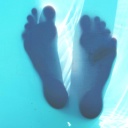 Transparente Unterseite eines Wasserbeckens, auf der sich die Silhouetten zweier Füße abzeichnen.