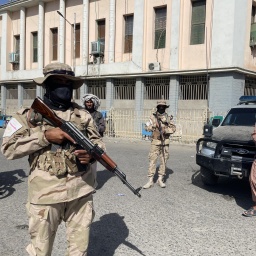 Taliban-Soldaten ergreifen Sicherheitsmaßnahmen auf der Straße und kontrollieren die Passanten. 
