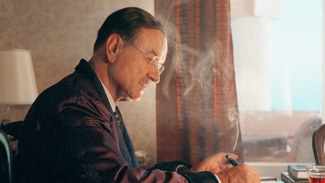 Thomas Mann (Armin Mueller-Stahl) in seinem Züricher Haus an seinem Schreibtisch, er hält eine rauchende Zigarre in der Hand und schreibt