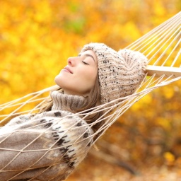 Eine Frau schläft in einer Hängematte in einem Herbstwald.