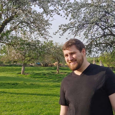 Jeremias Hubbauer in einem Park vor blühenden Obstbäumen