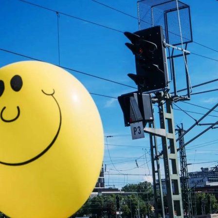 Luftballon mit Smiley auf Bahngleis
