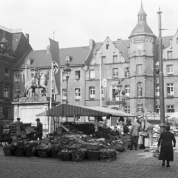 Gemüsemarkt in Düsseldorf in den 1930er-Jahren, gesäumt von Hakenkreuzfahnen.