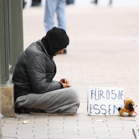 Ein Obdachloser sitzt bettelnd vor einem Geschäft in der Hamburger Innenstadt.