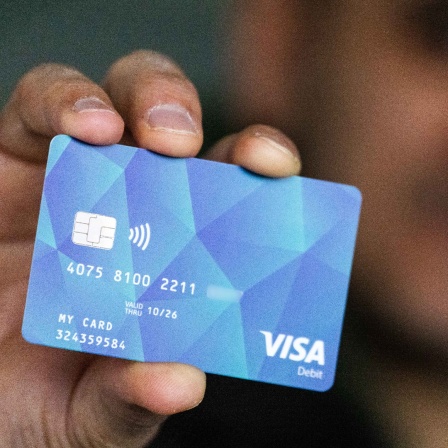 Ein Geflüchteter hält eine Debitcard in der Hand. 