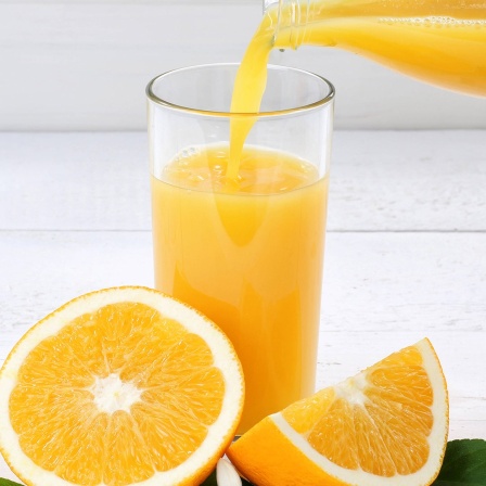 Orangensaft wird in ein Glas gegossen