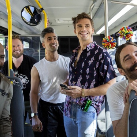 In einem Bus stehen und sitzen in fröhlicher Stimmung die 5 Akteure von "Queer Eye"