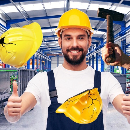 Mann mit Helm testet Helme, indem mit dem Hammer darauf geschlagen wird.