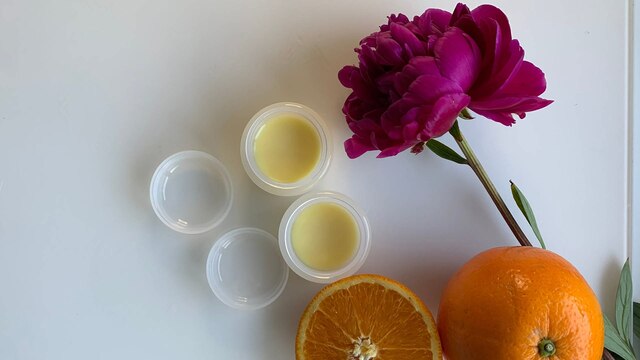 Selbstgemachter Lippenbalsam, Orangen und eine Blume