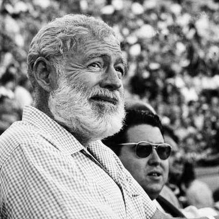 Schwarzweißporträt von Ernest Hemingway als älterem Mann in einem Stadion.