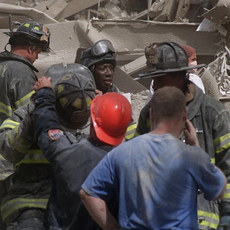 Feuerwehrleute durchsuchen die Trümmer, nachdem Terroristen am Dienstag, den 11. September 2001, zwei Flugzeuge in das World Trade Center in New York steuerten und die Türme zum Einsturz brachten