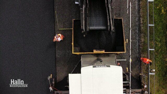 Bauarbeiter bringen neune Asphalt auf einem Autobahabschnitt auf..