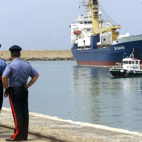Italienische Polizisten schauen am 12. Juli 2004 auf das deutsche Rettungsschiff &#034;Cap Anamur&#034; beim Anlegen im sizilianischen Hafen Porto Empedocle