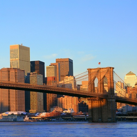 Brooklyn Bridge und East River bei Sonnenaufgang vor der Skyline von New York City